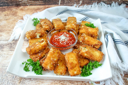 A platter of Fried Mozzarella Sticks with pizza sauce for dipping.