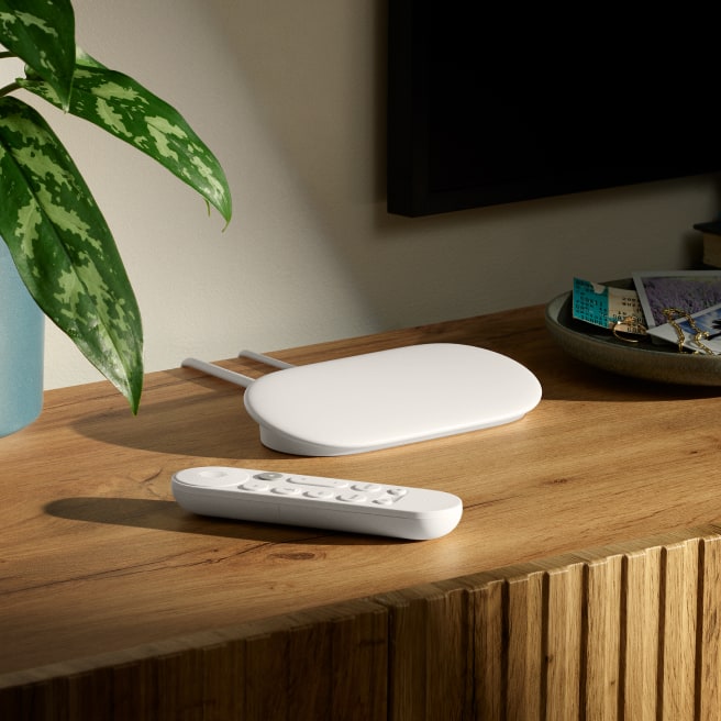 Google TV Streamer and its remote sit side by side on a table.