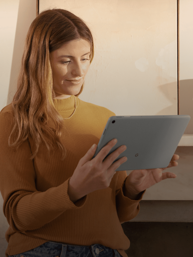 Una mujer sonríe mientras mira la pantalla de su tablet.
